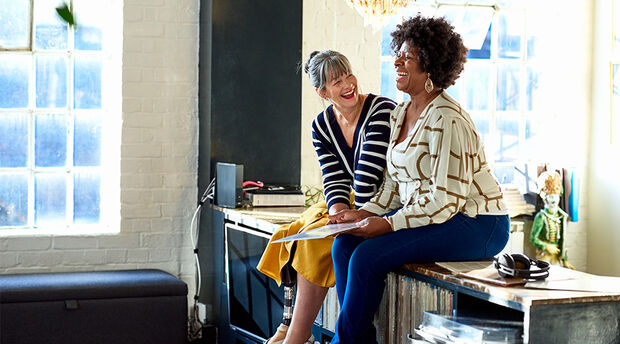 Two women sitting on sideboard laughing together
